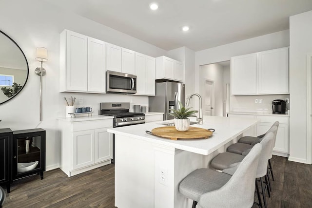 kitchen featuring white cabinetry, stainless steel appliances, and an island with sink