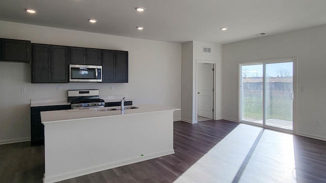 kitchen with stainless steel appliances, sink, a center island with sink, and dark hardwood / wood-style flooring