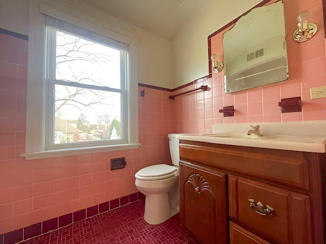 bathroom with tile patterned flooring, vanity, toilet, and tile walls