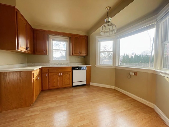 kitchen featuring sink, dishwasher, hanging light fixtures, and light wood-type flooring