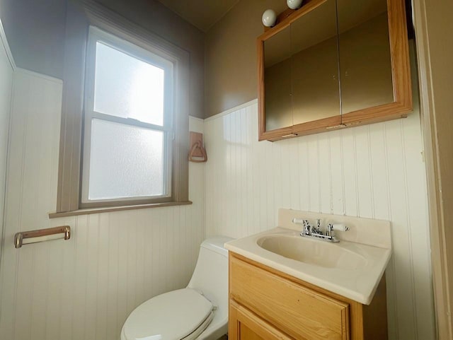 bathroom featuring vanity, toilet, and wooden walls