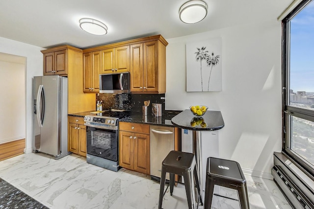 kitchen with backsplash, appliances with stainless steel finishes, and dark stone countertops