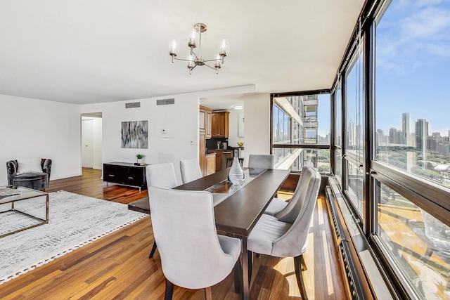 dining space featuring a wall of windows, wood-type flooring, and a notable chandelier