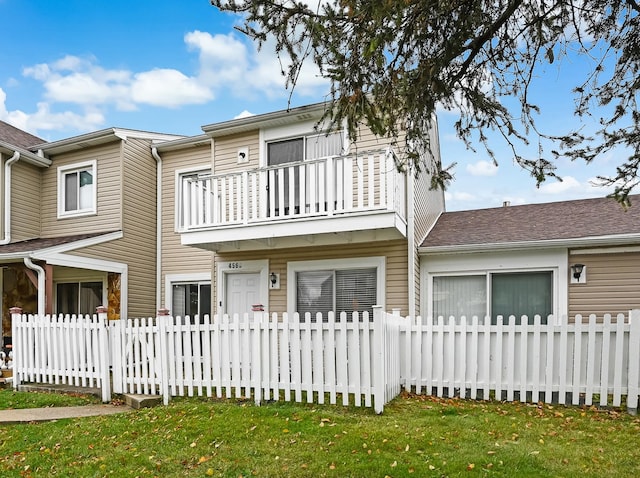 rear view of house with a lawn and a balcony