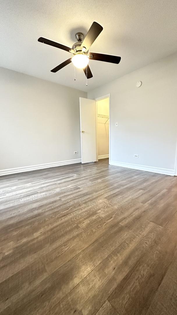 unfurnished room with ceiling fan, dark wood-type flooring, and a textured ceiling