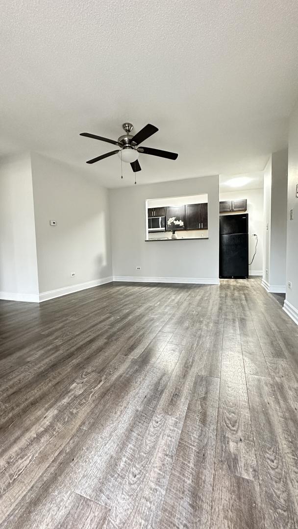 unfurnished living room with ceiling fan, hardwood / wood-style floors, and a textured ceiling