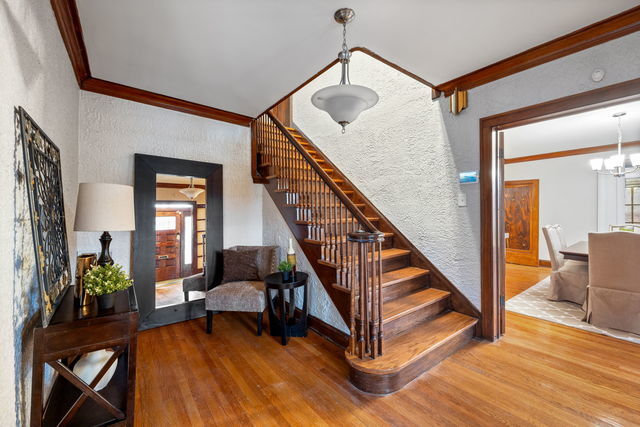 stairs with an inviting chandelier, ornamental molding, and hardwood / wood-style flooring