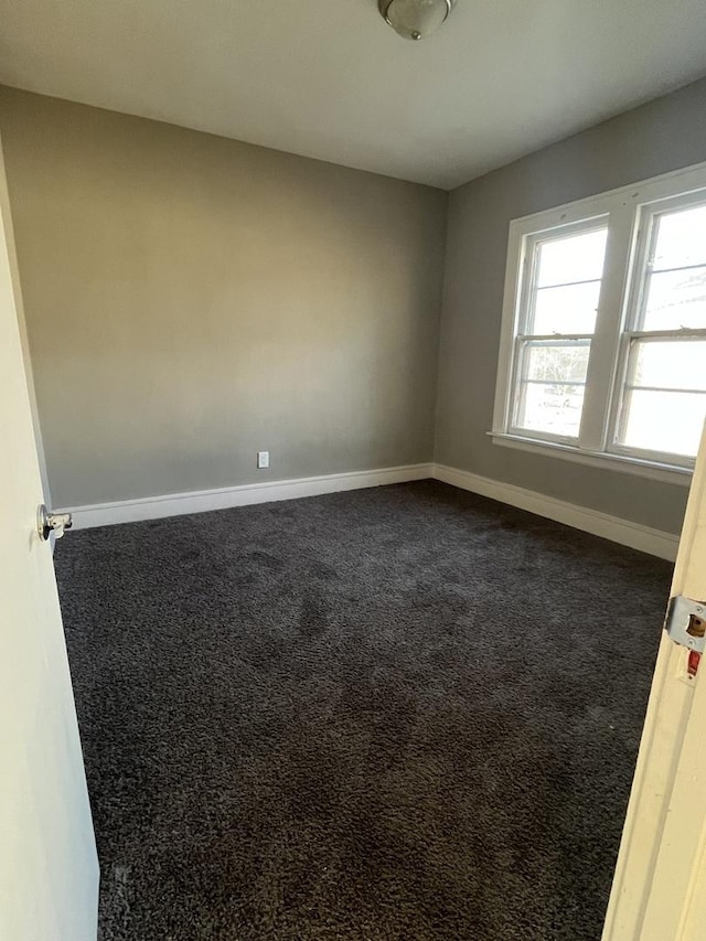 unfurnished room featuring dark carpet