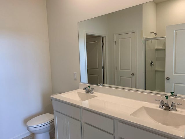 bathroom featuring vanity, a shower with shower door, and toilet