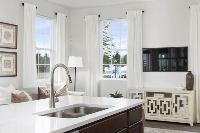 kitchen with dark wood-type flooring, dark brown cabinets, a healthy amount of sunlight, and sink