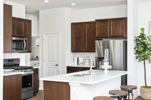 kitchen with a kitchen bar, a kitchen island with sink, sink, dark hardwood / wood-style flooring, and stainless steel appliances