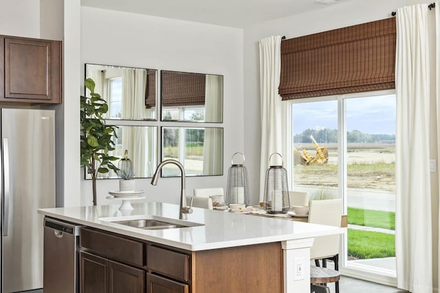 kitchen featuring a breakfast bar, appliances with stainless steel finishes, a center island with sink, and sink