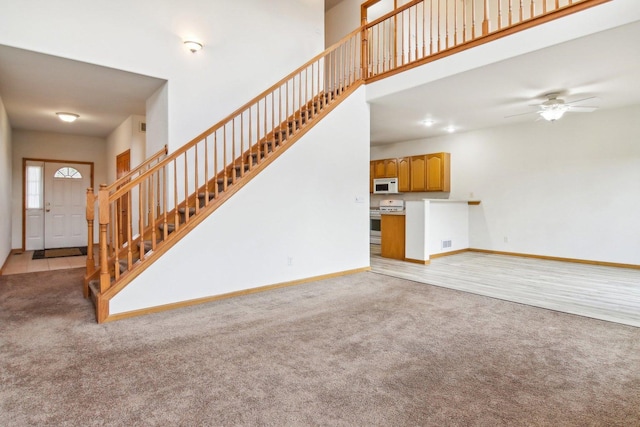 unfurnished living room featuring light colored carpet and ceiling fan