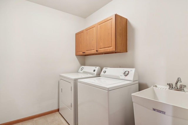 clothes washing area featuring cabinets, sink, and washer and dryer