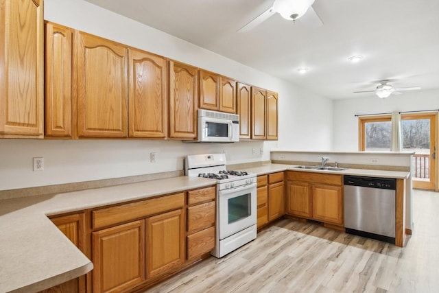 kitchen featuring ceiling fan, white appliances, light hardwood / wood-style floors, and sink