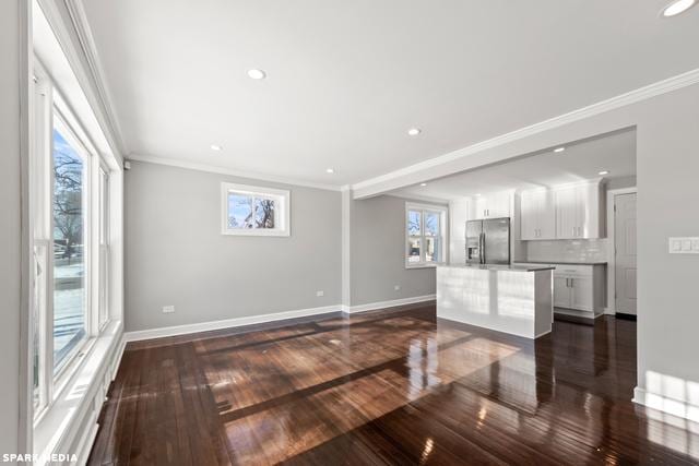 unfurnished living room featuring dark hardwood / wood-style floors, ornamental molding, and a wealth of natural light