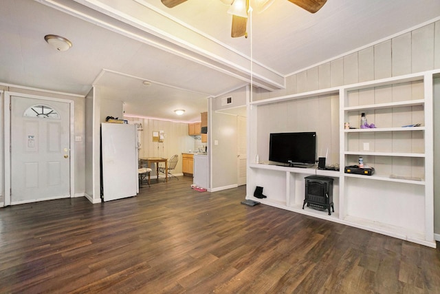 unfurnished living room with ceiling fan, dark hardwood / wood-style flooring, lofted ceiling with beams, wood walls, and ornamental molding