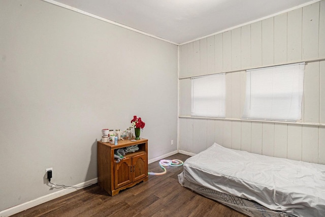 bedroom featuring wood walls, crown molding, and dark wood-type flooring