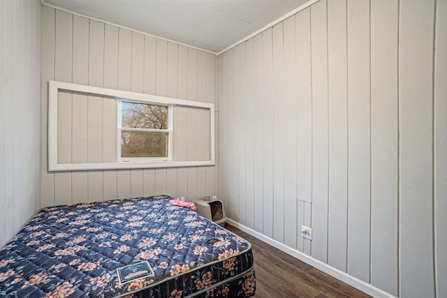 bedroom with dark hardwood / wood-style floors and wooden walls