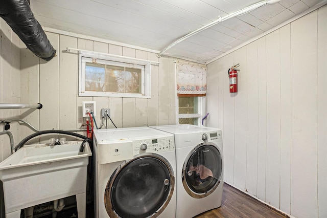 washroom featuring dark hardwood / wood-style flooring, washing machine and dryer, wooden walls, and sink