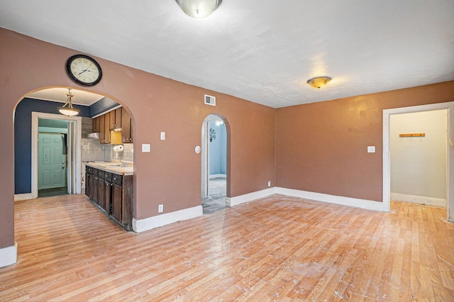 kitchen featuring dark brown cabinets, light wood-type flooring, sink, and tasteful backsplash