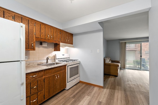 kitchen featuring light wood-type flooring, white appliances, sink, and tasteful backsplash