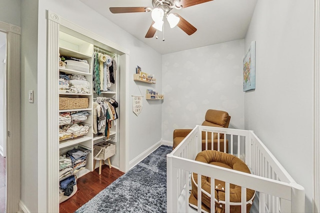 bedroom featuring ceiling fan, a closet, a nursery area, and dark hardwood / wood-style floors