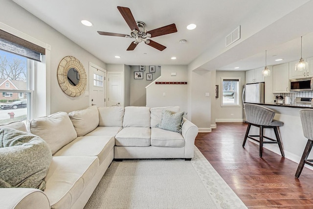 living room featuring dark hardwood / wood-style floors, ceiling fan, and a wealth of natural light