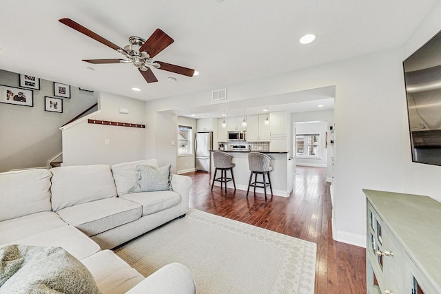 living room with ceiling fan and dark wood-type flooring