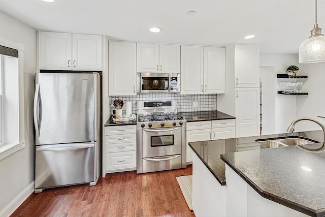 kitchen with white cabinets, sink, appliances with stainless steel finishes, decorative light fixtures, and dark hardwood / wood-style flooring