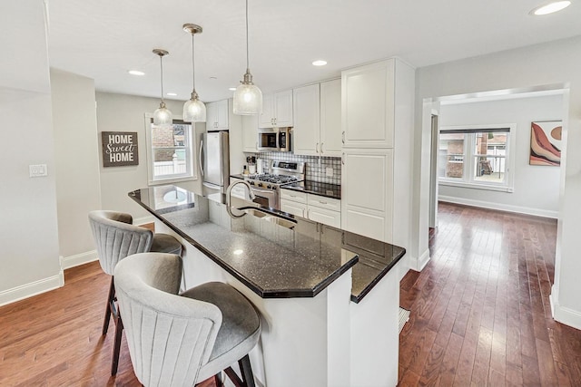 kitchen featuring plenty of natural light, white cabinets, hanging light fixtures, and appliances with stainless steel finishes