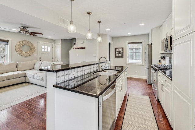 kitchen with stainless steel appliances, dark wood-type flooring, sink, pendant lighting, and white cabinets