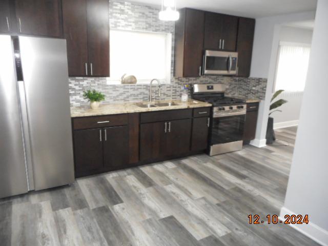 kitchen with sink, stainless steel appliances, plenty of natural light, and light hardwood / wood-style floors