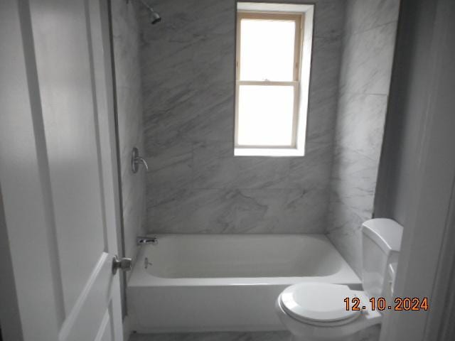 bathroom with tiled shower / bath combo and toilet