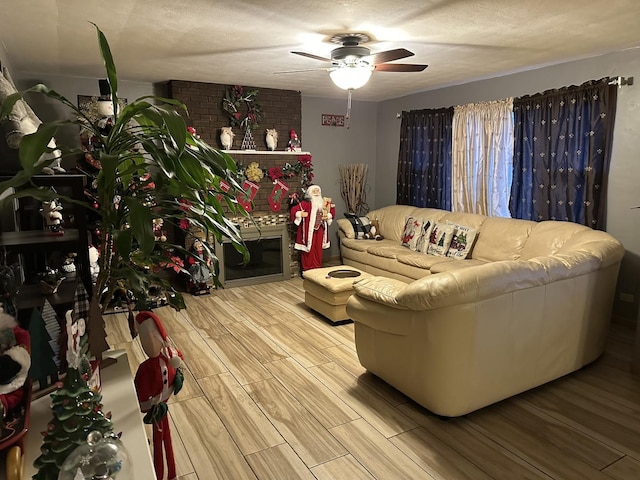 living room featuring hardwood / wood-style flooring, ceiling fan, and a textured ceiling