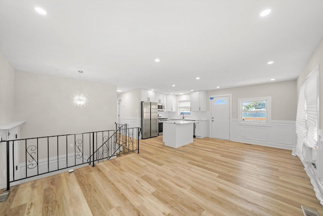 kitchen featuring a center island, hanging light fixtures, appliances with stainless steel finishes, light hardwood / wood-style floors, and white cabinetry