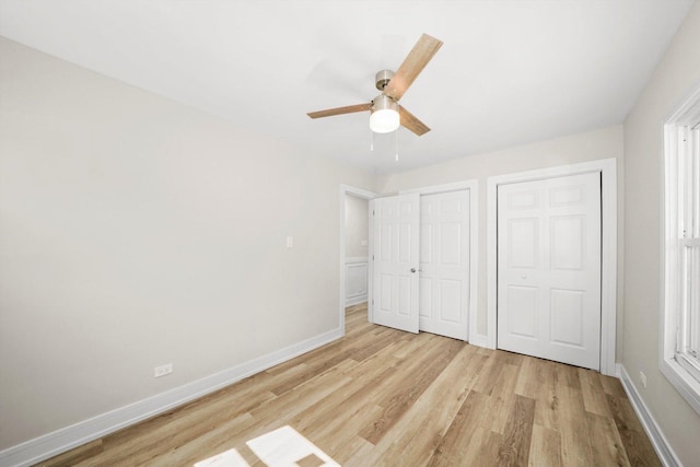 unfurnished bedroom featuring multiple closets, ceiling fan, and light hardwood / wood-style floors