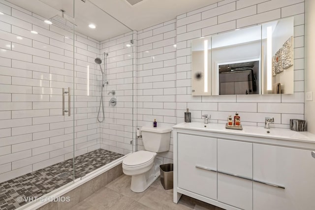 bathroom featuring vanity, a shower with door, decorative backsplash, toilet, and tile walls