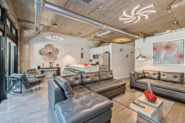 living area with a chandelier, light wood-style flooring, and track lighting