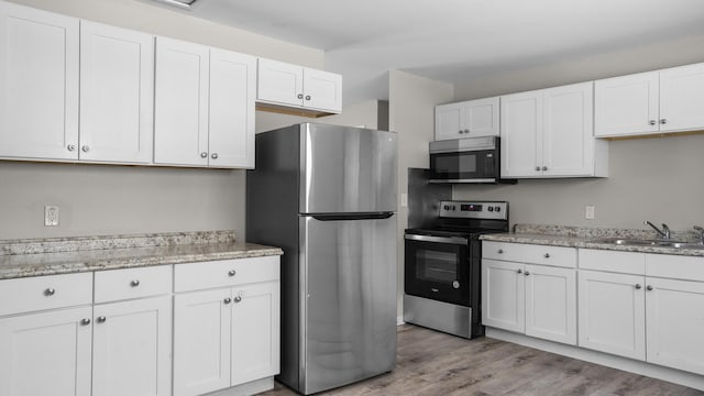 kitchen featuring white cabinetry, sink, light wood-type flooring, and appliances with stainless steel finishes