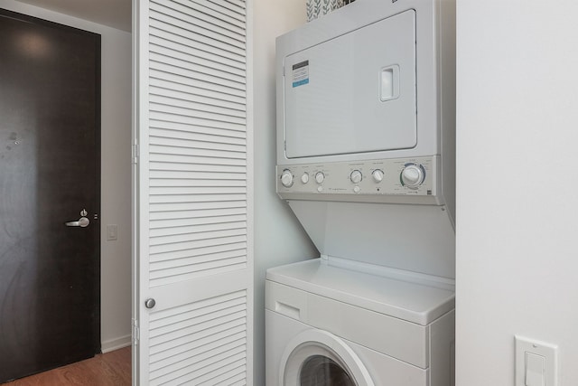 laundry area with dark hardwood / wood-style flooring and stacked washer / dryer