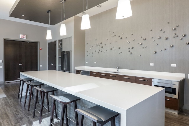 kitchen with a kitchen bar, decorative light fixtures, appliances with stainless steel finishes, a large island, and dark hardwood / wood-style flooring