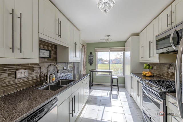 kitchen with backsplash, white cabinets, sink, dark stone countertops, and stainless steel appliances