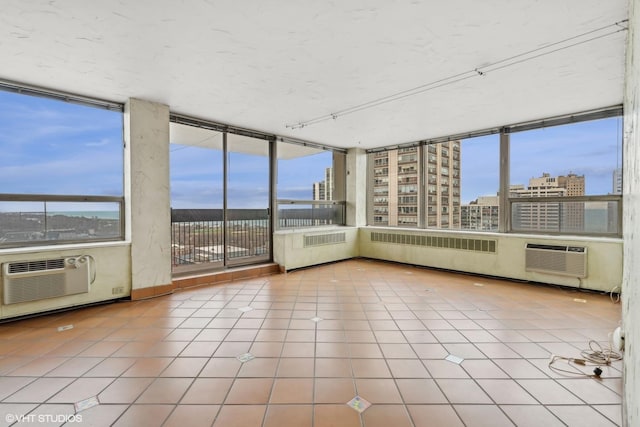 unfurnished sunroom featuring radiator heating unit and a wall mounted air conditioner