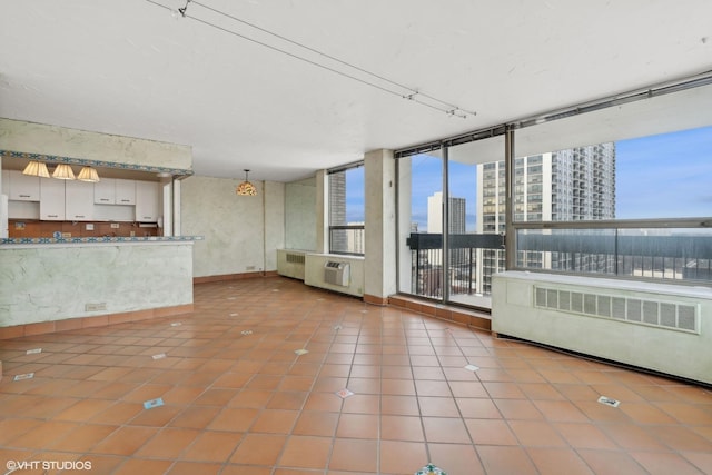 unfurnished living room with a chandelier, radiator heating unit, and tile patterned floors