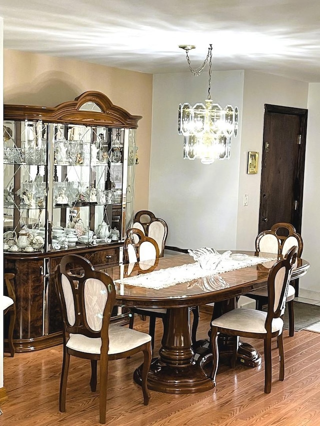 dining area featuring wood-type flooring and an inviting chandelier