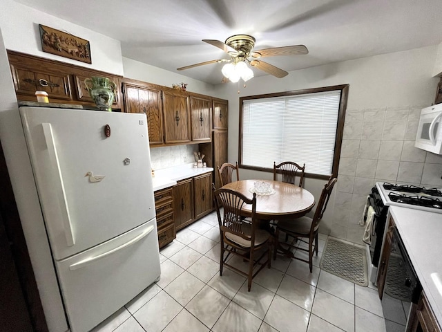 kitchen featuring ceiling fan, backsplash, white appliances, light tile patterned flooring, and tile walls