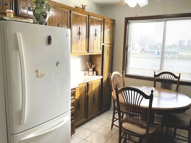 kitchen with ceiling fan, white refrigerator, dark brown cabinetry, and light tile patterned floors