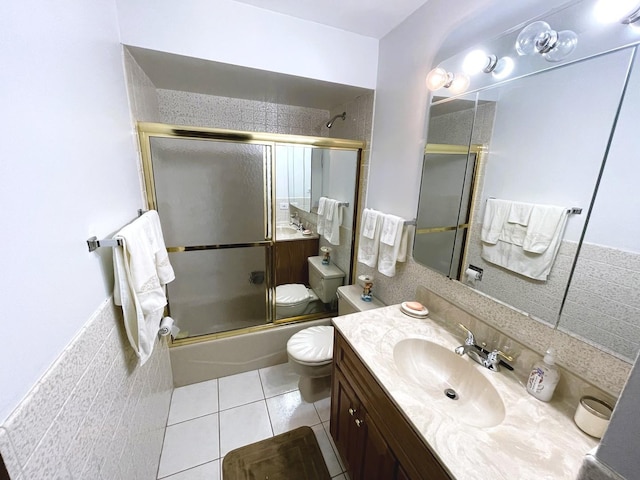 full bathroom featuring vanity, combined bath / shower with glass door, tile patterned flooring, toilet, and tile walls