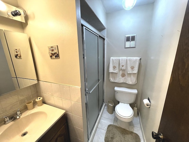 bathroom with tile patterned floors, vanity, an enclosed shower, and tile walls